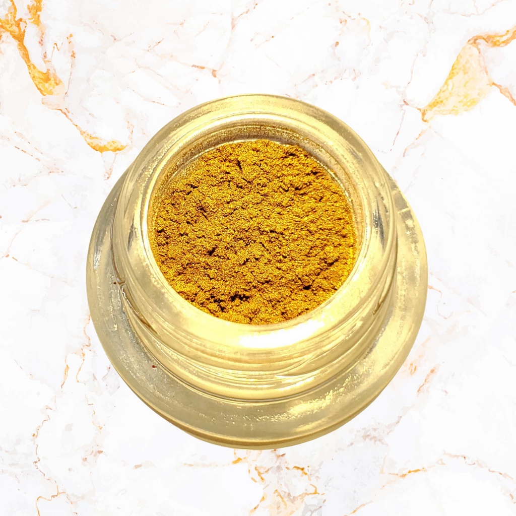 Jar of gold powder on a marble surface